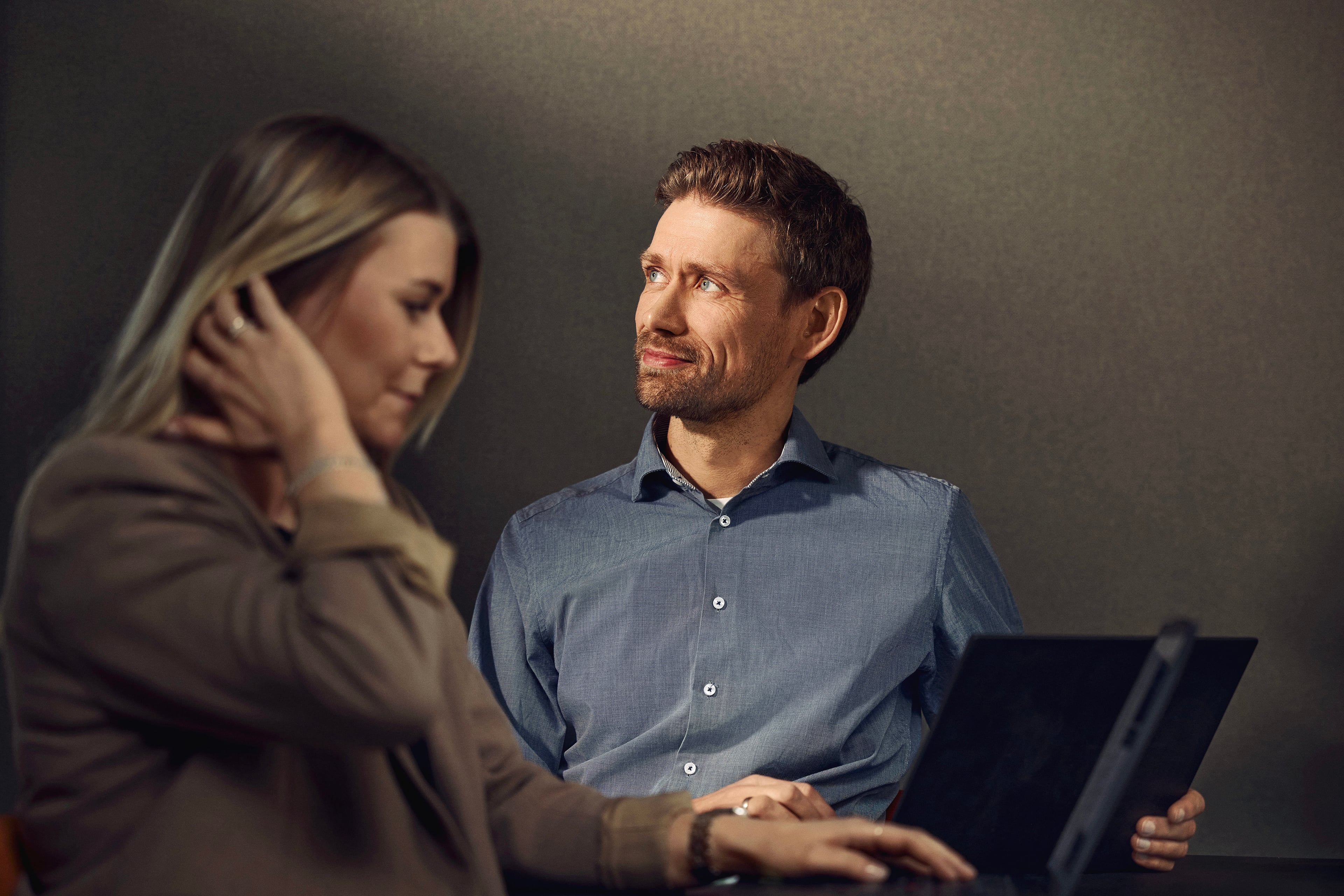 Mand og kvinde arbejder sammen ved tablet mod neutral baggrund